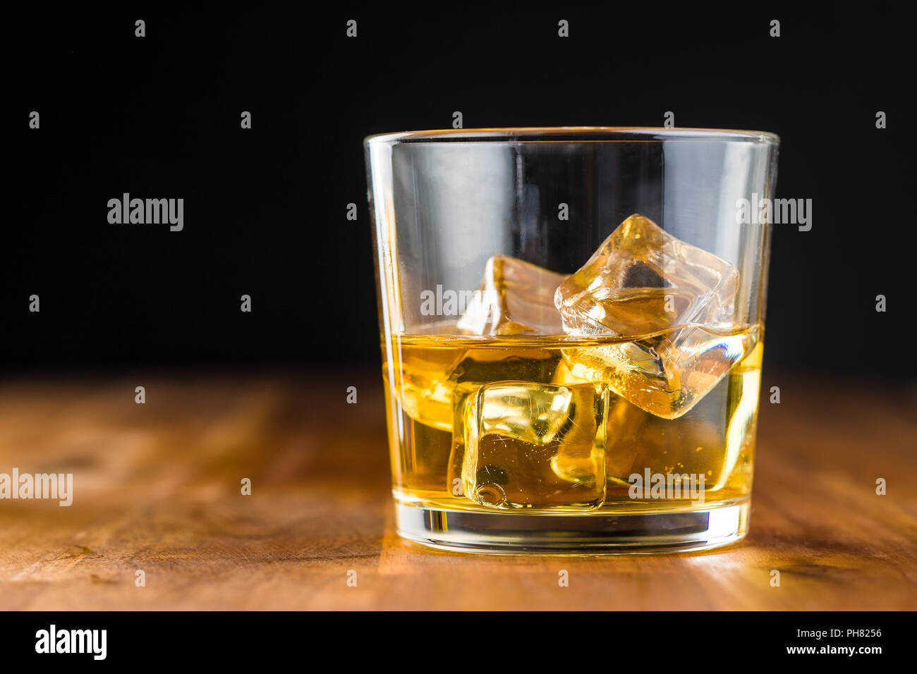 Glas alkoholische Getränke mit Eiswürfeln auf hölzernen Tisch. Whiskey in Glas. Stockfoto