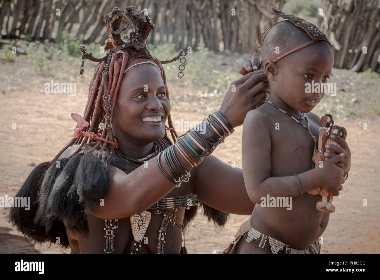 Ovahimba oder Himba, eine Mutter bringt Kopfschmuck auf ihrem Sohn, Kunene, Namibia Stockfoto