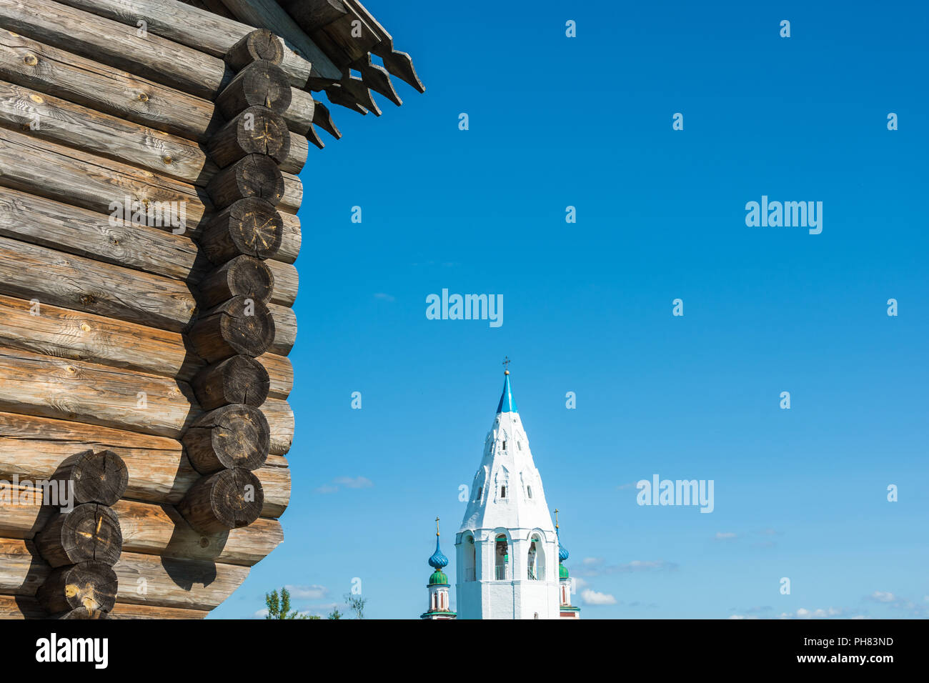 Holz- Mauern einer alten Festung und schneeweißen Wänden eines hohen Glockenturm vor blauem Himmel. Stockfoto