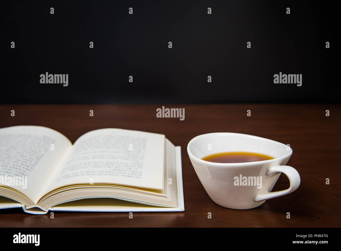 Öffnen Sie ein Buch auf dem Schreibtisch mit einer Tasse Kaffee Stockfoto