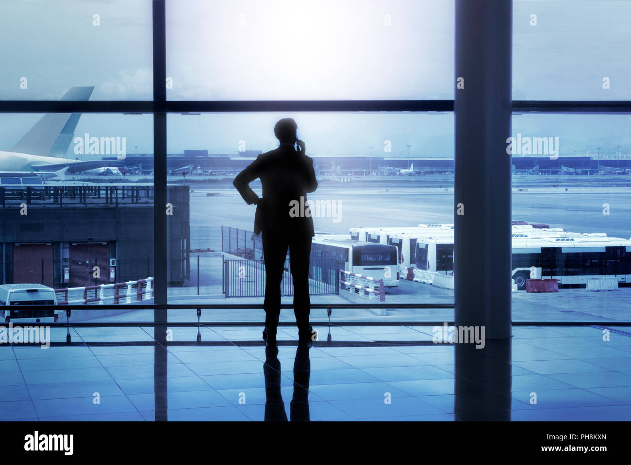 Geschäftsmann Silhouette der Aufruf in der Flughafen Lobby vor Fenstern Stockfoto