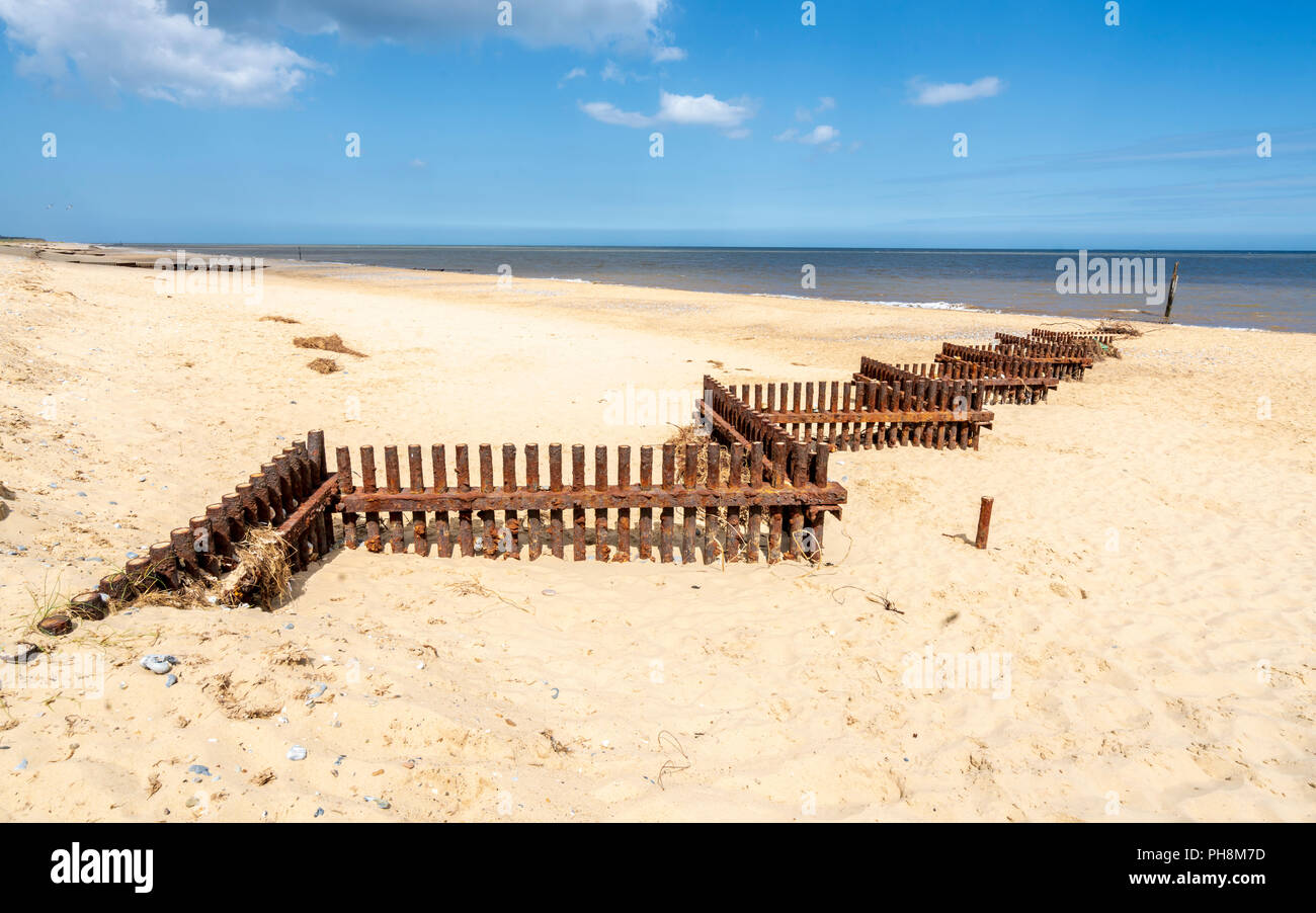 Rostigem Eisen Sturm Verteidigung Barrieren auf einem sandigen Strand von Norfolk in Großbritannien Stockfoto