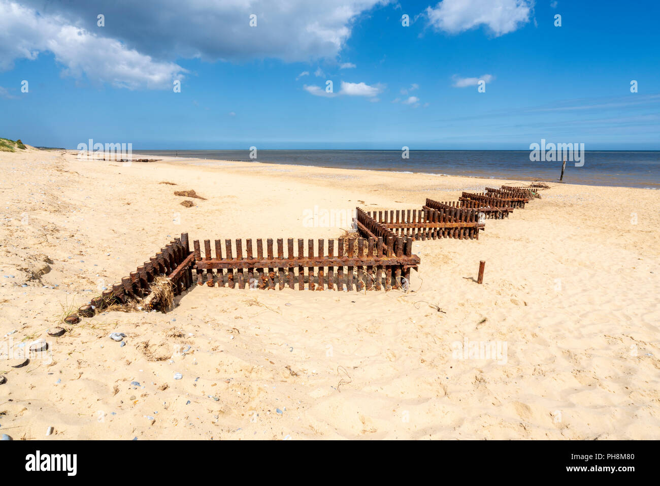 Rostigem Eisen Sturm Verteidigung Barrieren Zickzack entlang der sandigen Strand von Norfolk in Großbritannien Stockfoto