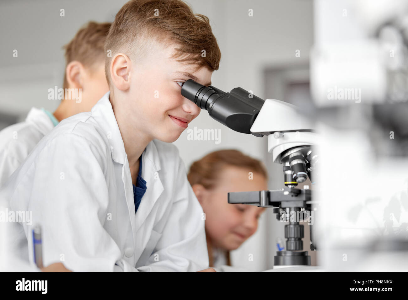 Kinder, Schüler oder Studenten mit Mikroskop Biologie in der Schule Stockfoto