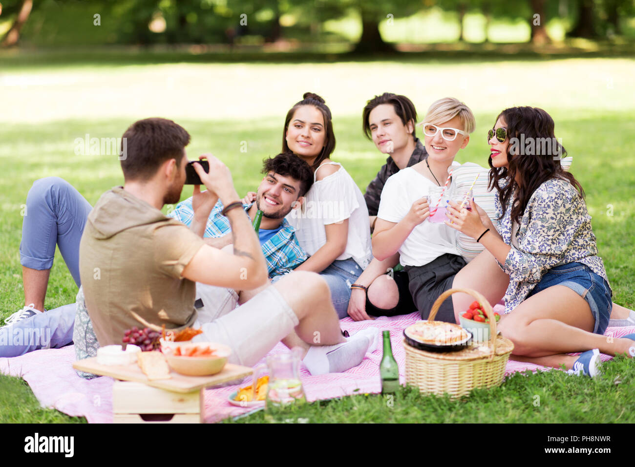 Freunde fotografieren im Sommer Picknick im Park Stockfoto