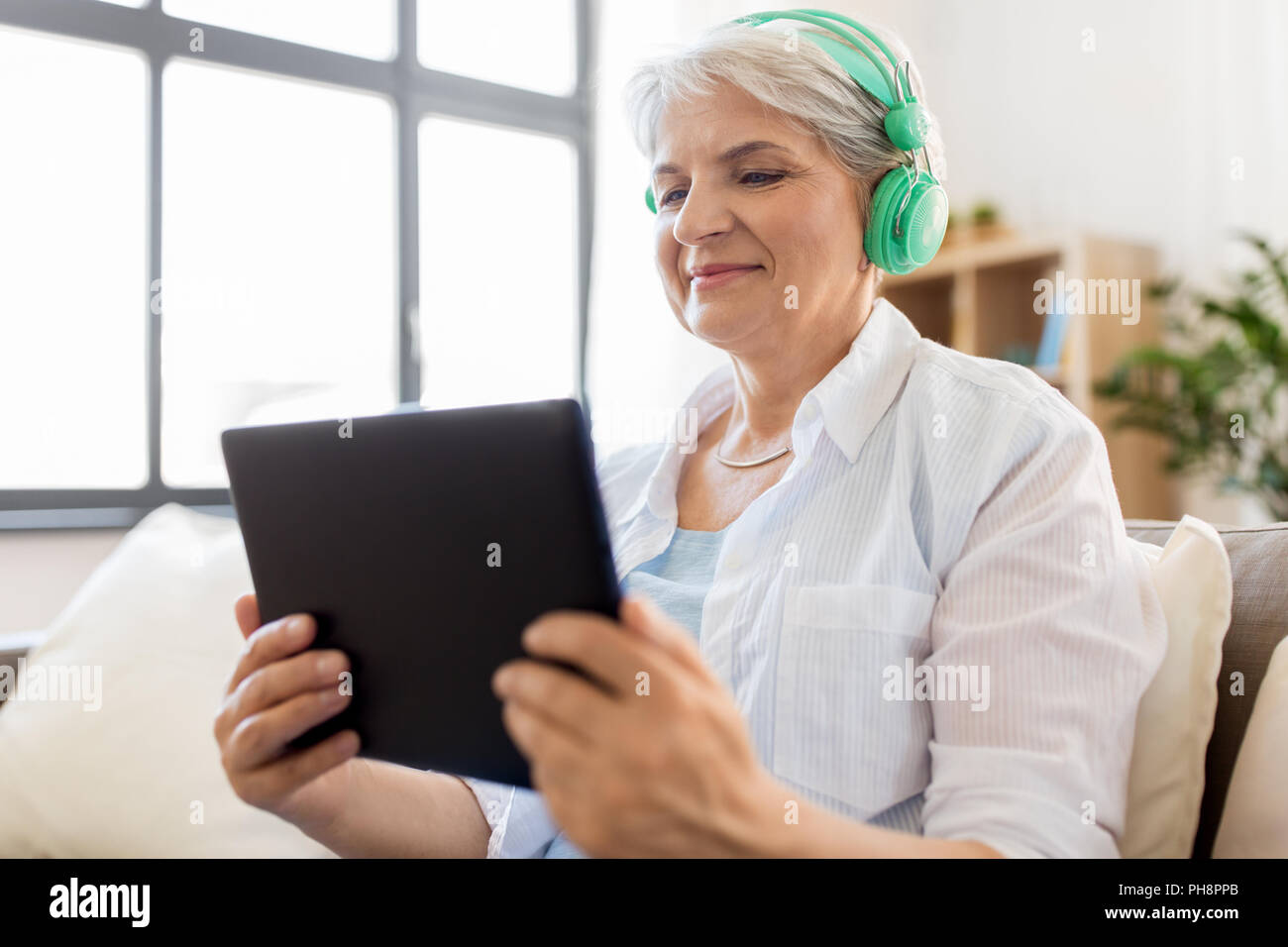 Ältere Frau in Kopfhörer Musik hören Stockfoto