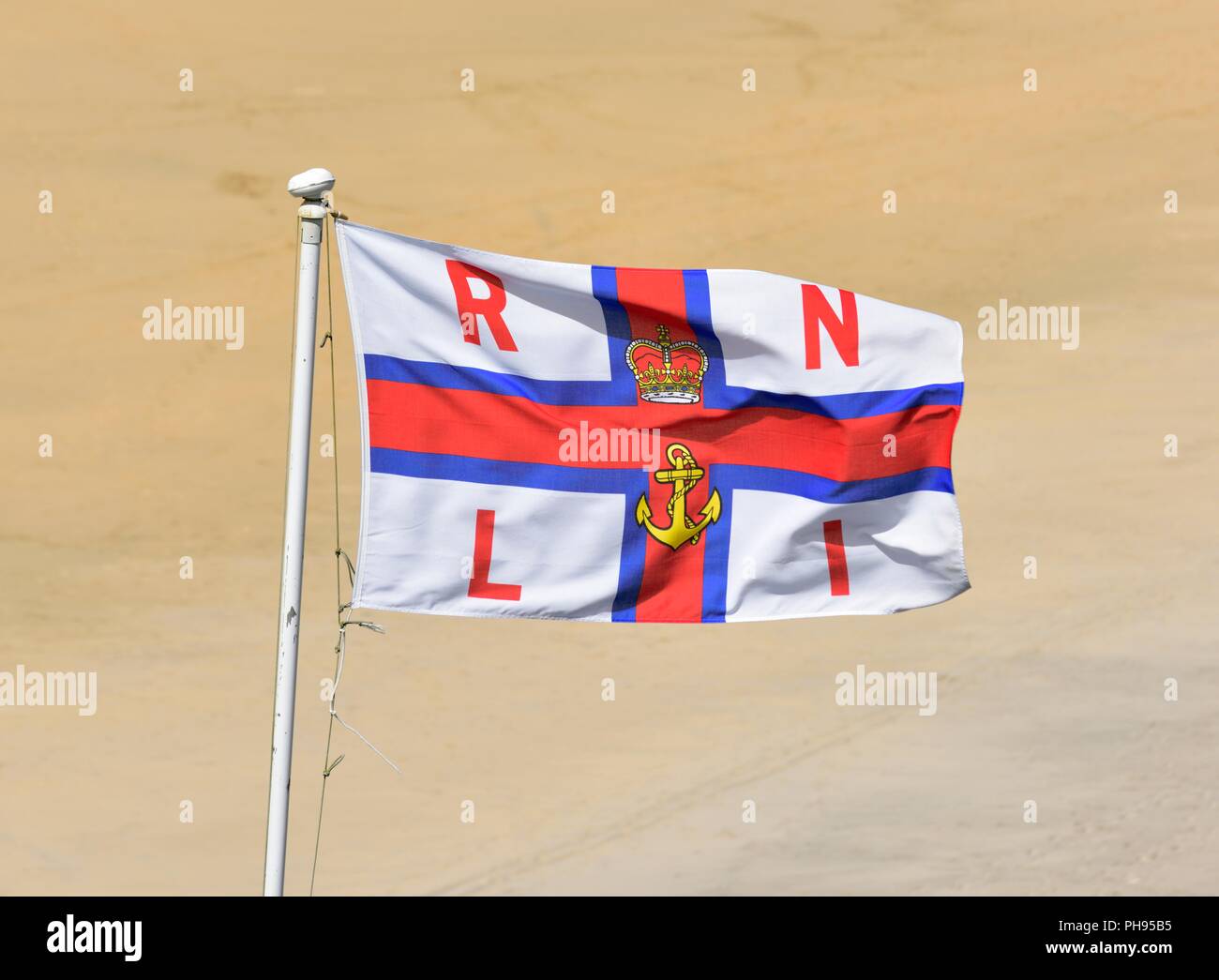 Royal National Lifeboat Institution Flagge, RNLI ensign Flagge gegen einen Sandstrand Boden zurück Stockfoto