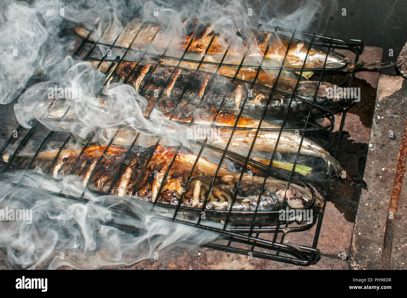 Makrelen gegrillter Fische Eisenplatte in ländlichen Haus Kamin closeup mit weißer Rauch Stockfoto