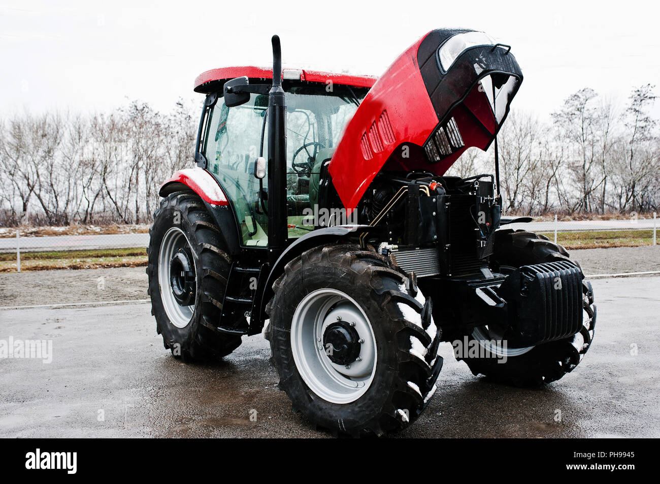 Neue rote Traktor mit offenen Motor bei Schneewetter Stockfoto