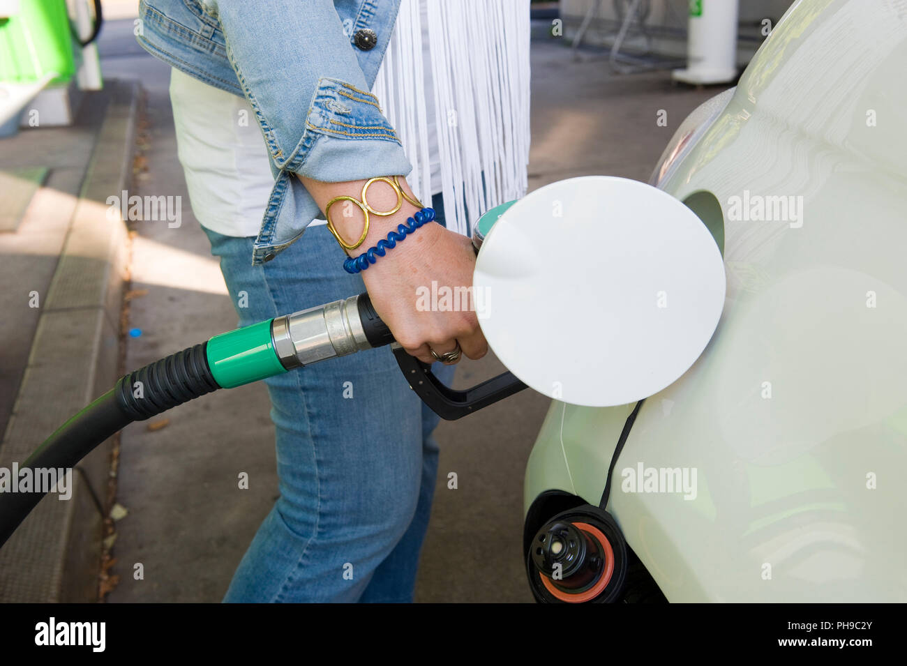 Eine Frau ist ihr Auto mit Kraftstoff an der Tankstelle befüllen. Stockfoto