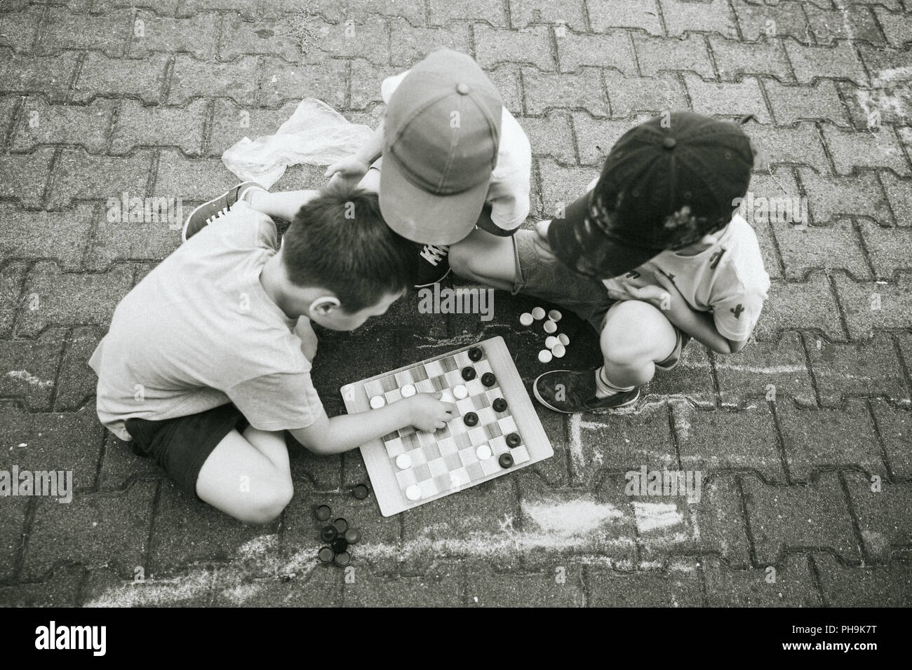 Drei Jungen spielen Checkers Board Spiel im Freien. Stockfoto