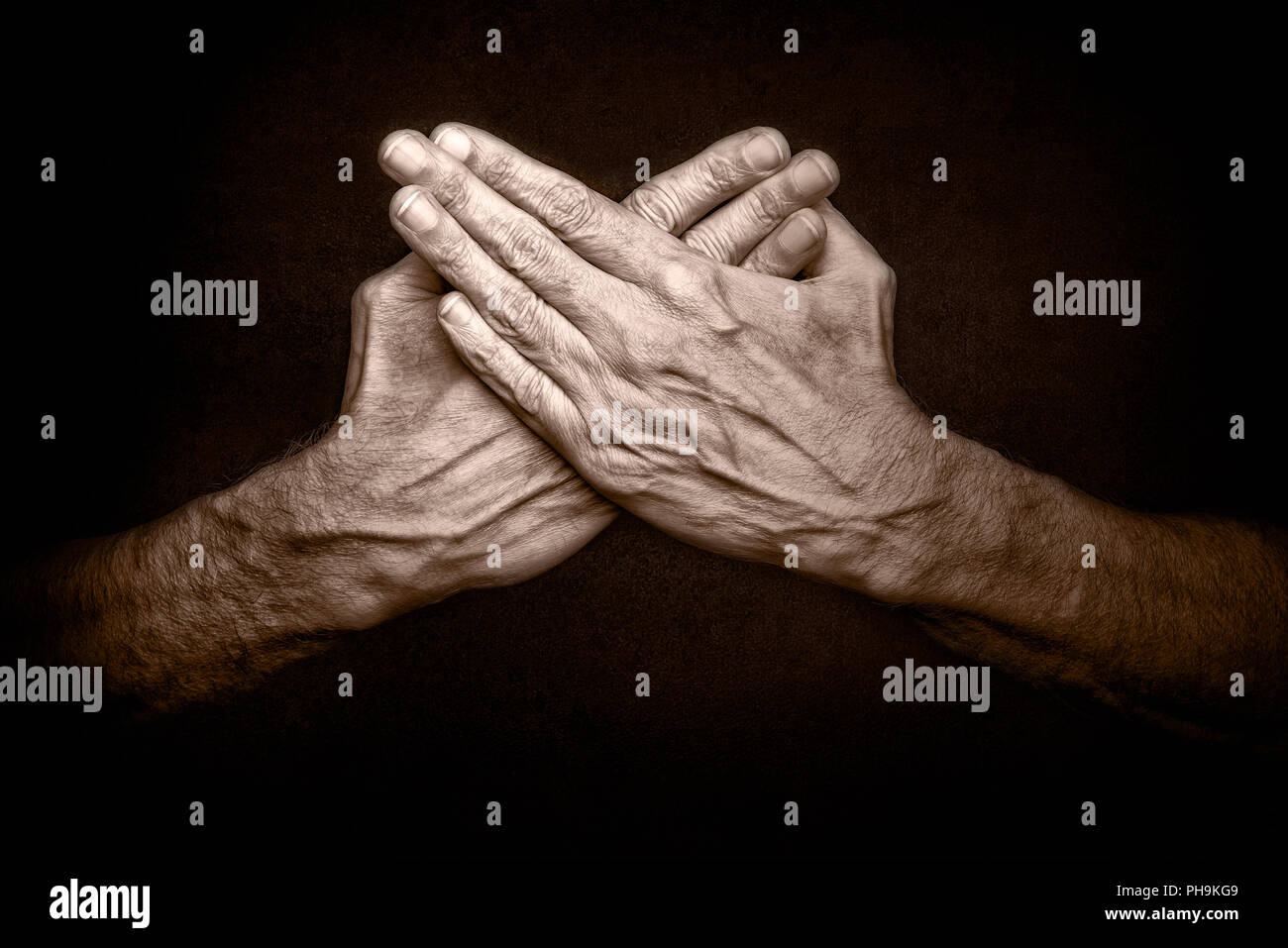 Foto der gekreuzten Hände des Menschen auf dunklem Hintergrund, Symbol für Schutz der Sicherheit Stockfoto