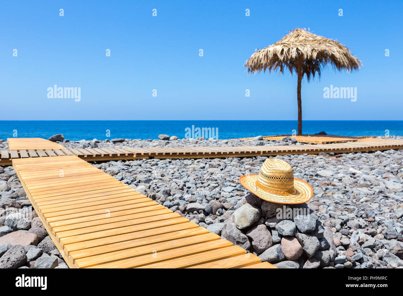Portugiesische steinigen Strand mit Pfad meer Hut und Sonnenschirm Stockfoto