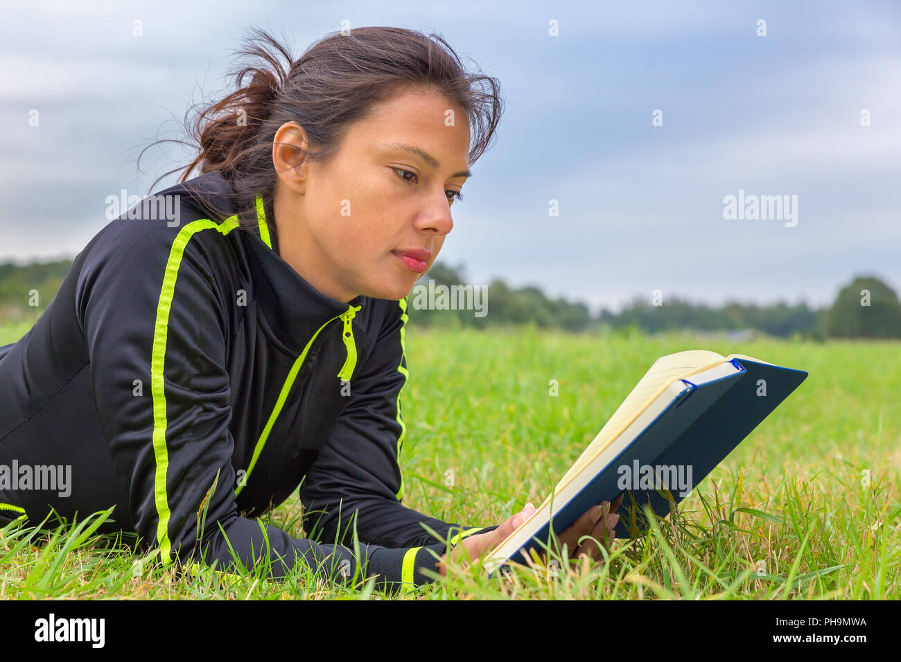 Niederländische Frau im Gras liegend lesen Buch Stockfoto