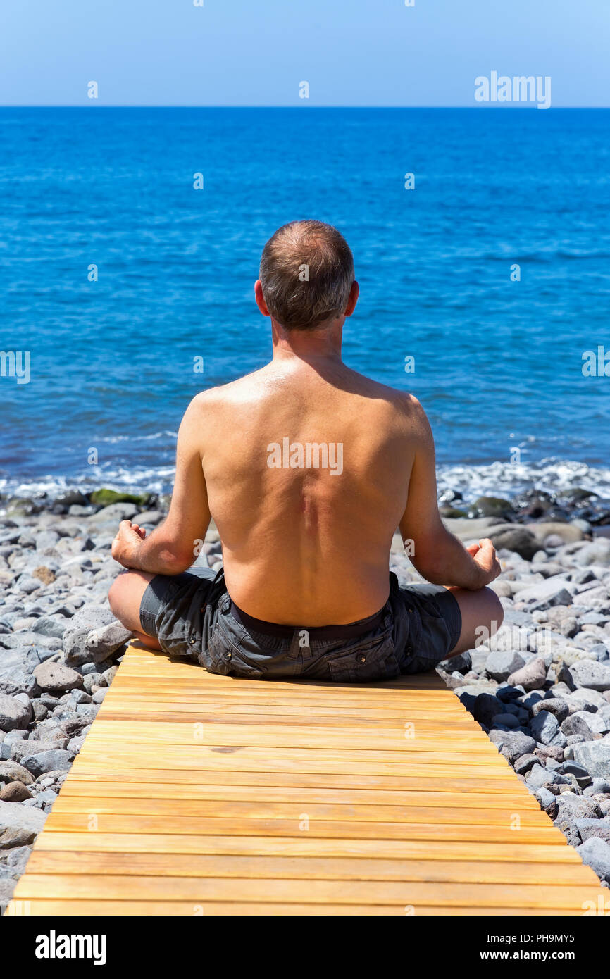 Man meditieren an Strand und Meer Stockfoto