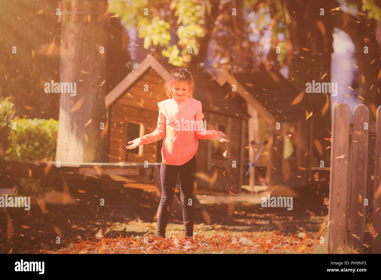 Junge Mädchen spielen mit fallenden Blätter im Herbst Stockfoto