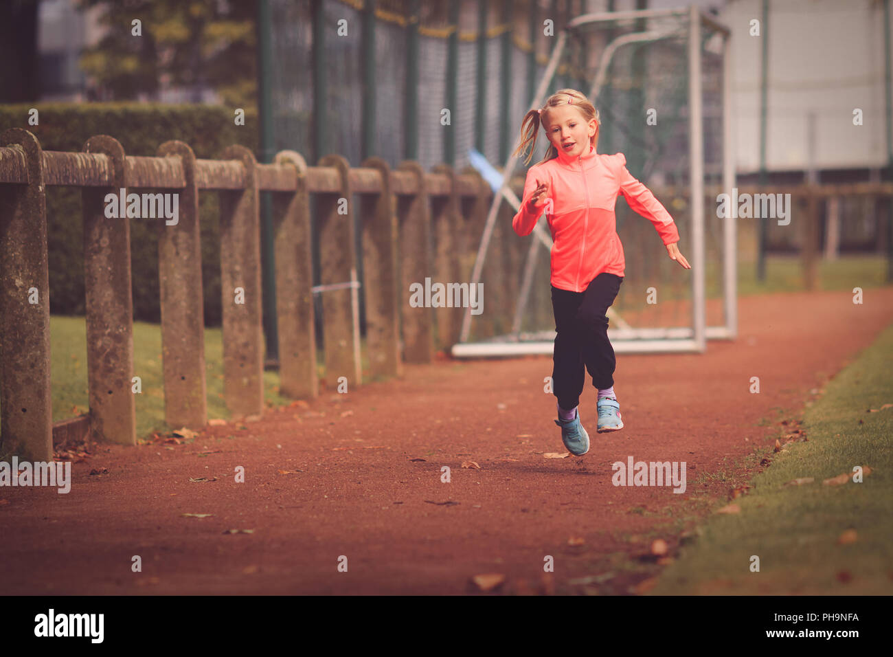 Junge Mädchen im Alter von 5 bis 7 läuft auf athletischen Rennstrecke Stockfoto