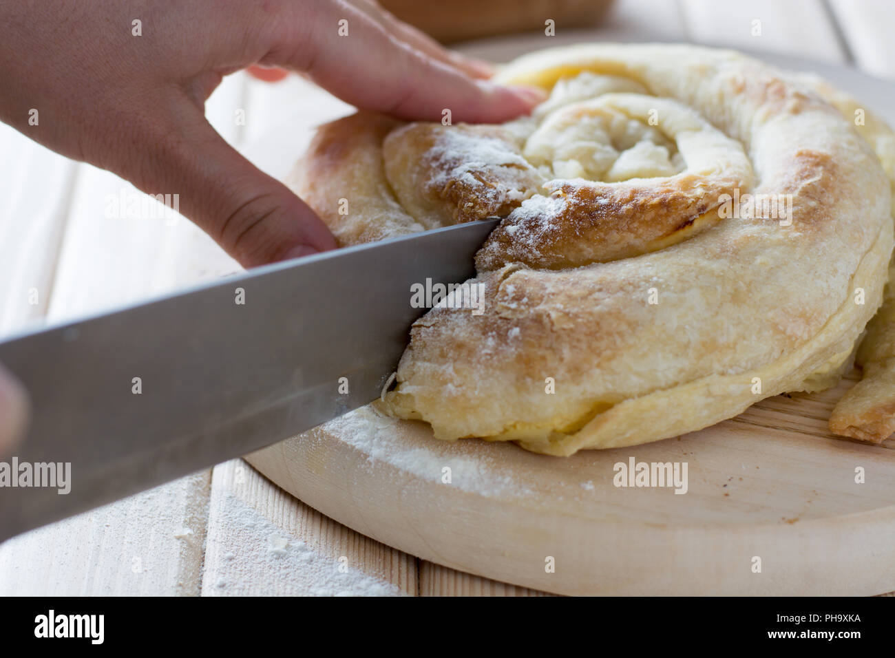 Weibliche Hände schneiden frisch gebackenen Käse torte Stockfoto
