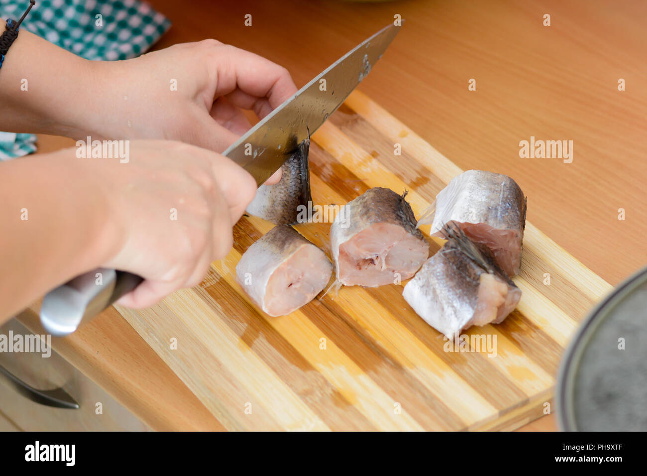 Weibliche Hände mit Messer schneiden fischen Seehecht Stockfoto