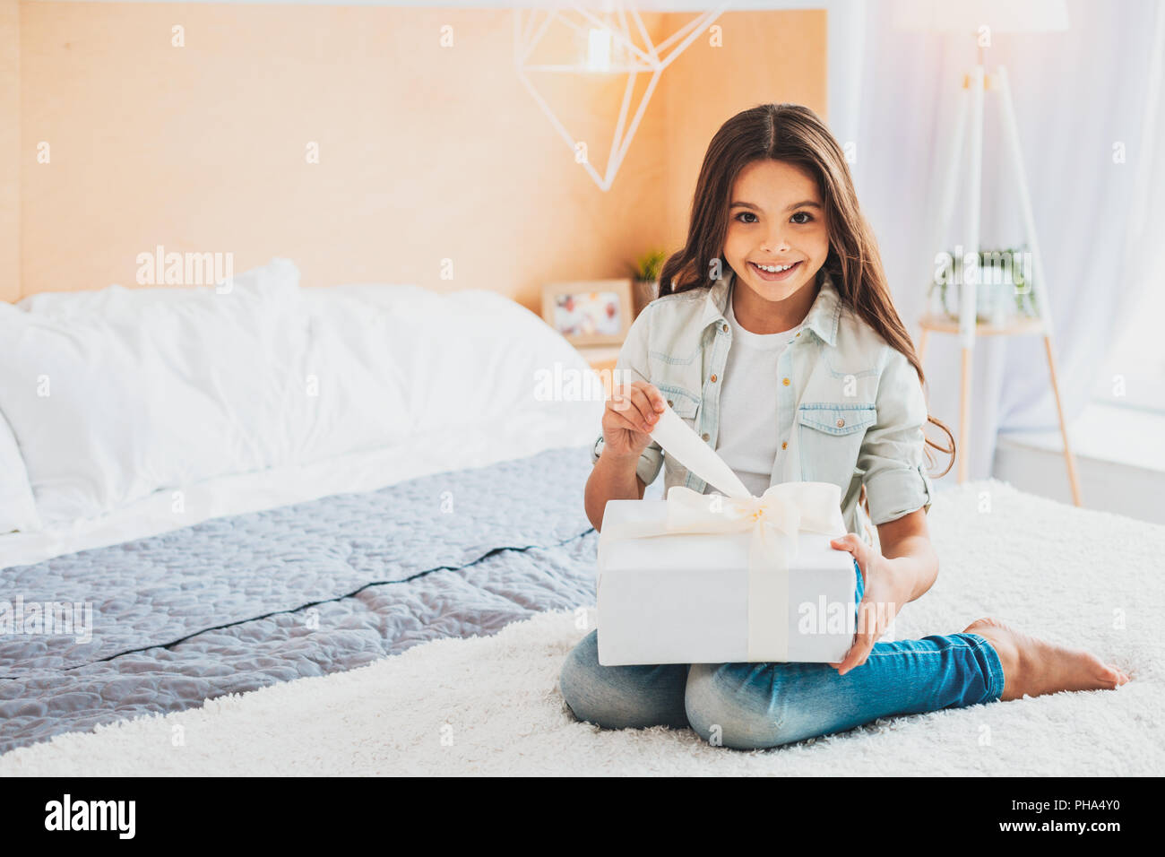 Neugierige Schülerin Eröffnung anwesend, sitzen auf dem Bett Stockfoto