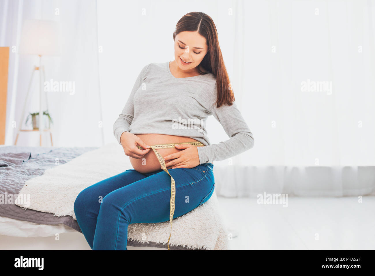 Charmantes hübsches erwartet Frau sitzt auf der großen Doppelbett Stockfoto