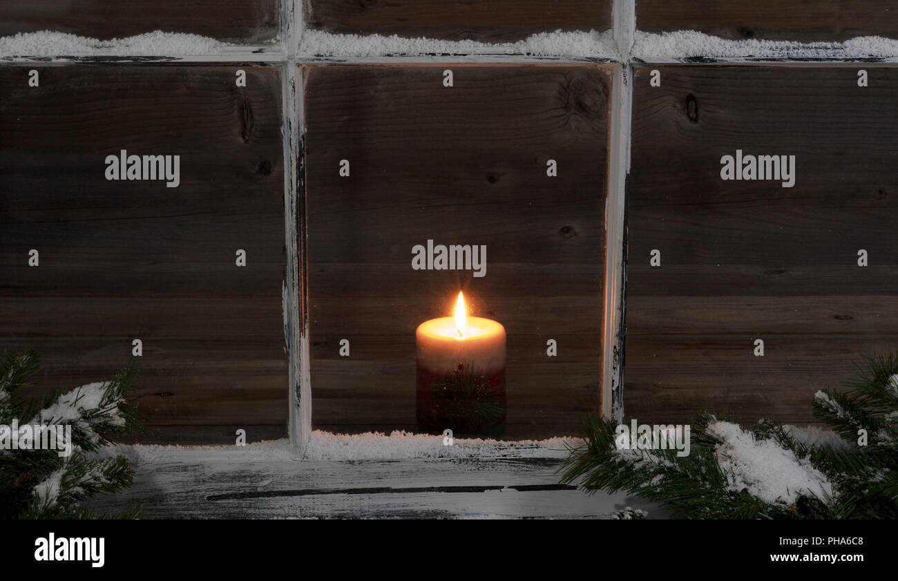 Verschneite Fenster und Tannenzweigen mit leuchtenden Kerze Stockfoto