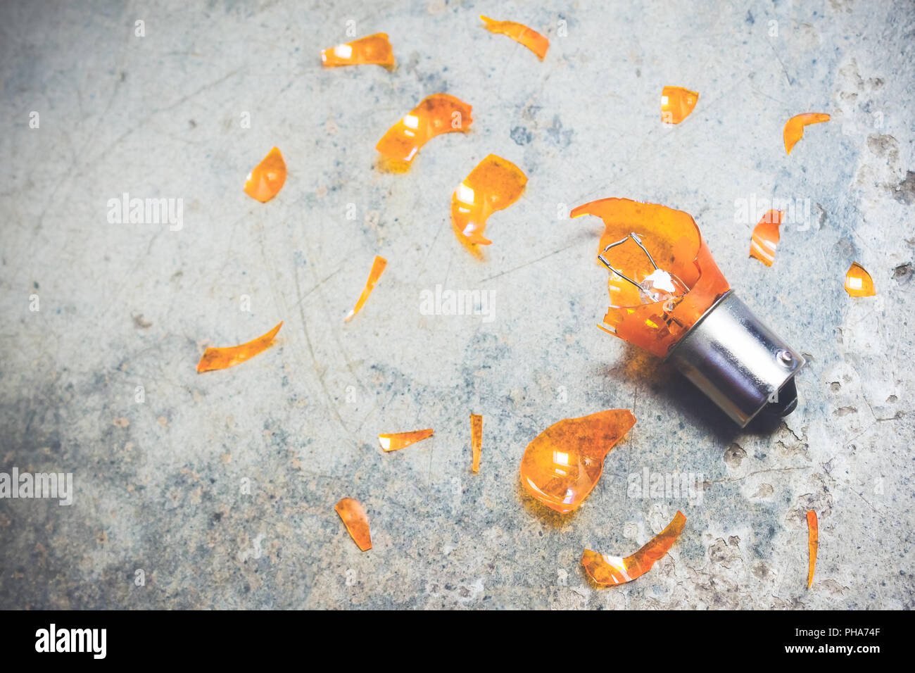 Automotive Glühbirne in defektem Zustand und scharfe Glasscherben um es auf strukturierten Hintergrund verstreut. Stockfoto