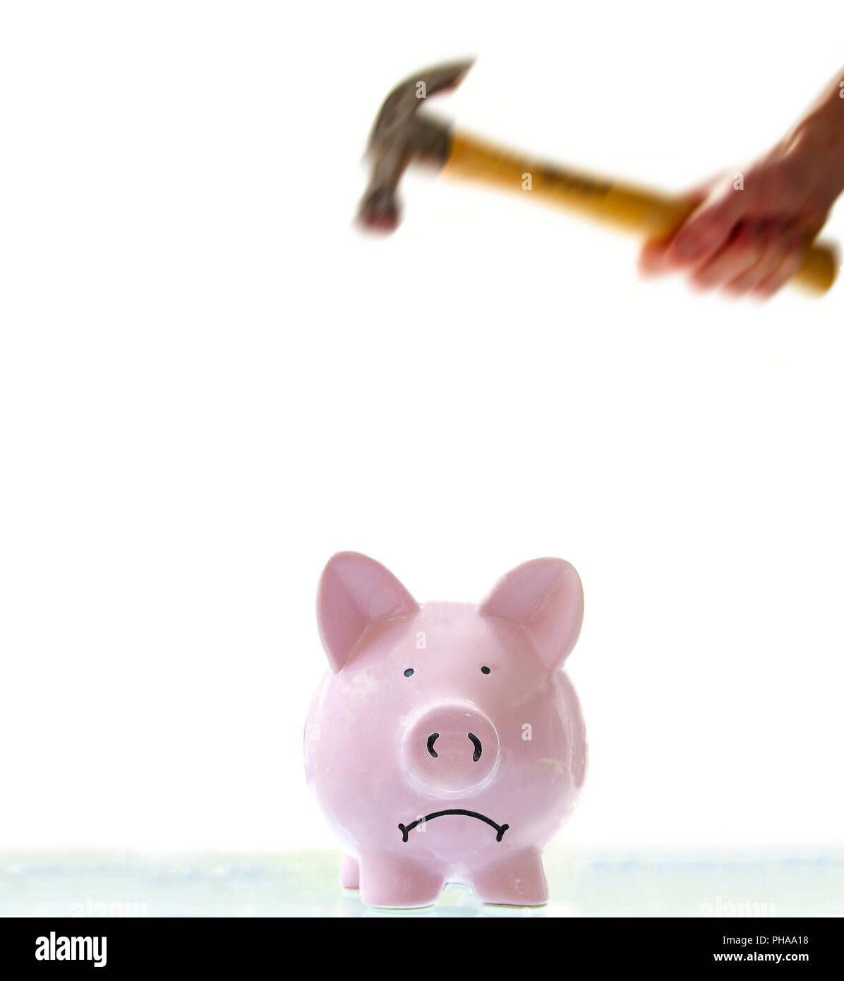 Stirnrunzelnd Sparschwein zu zerschlagen, indem mit einem Hammer. Stockfoto
