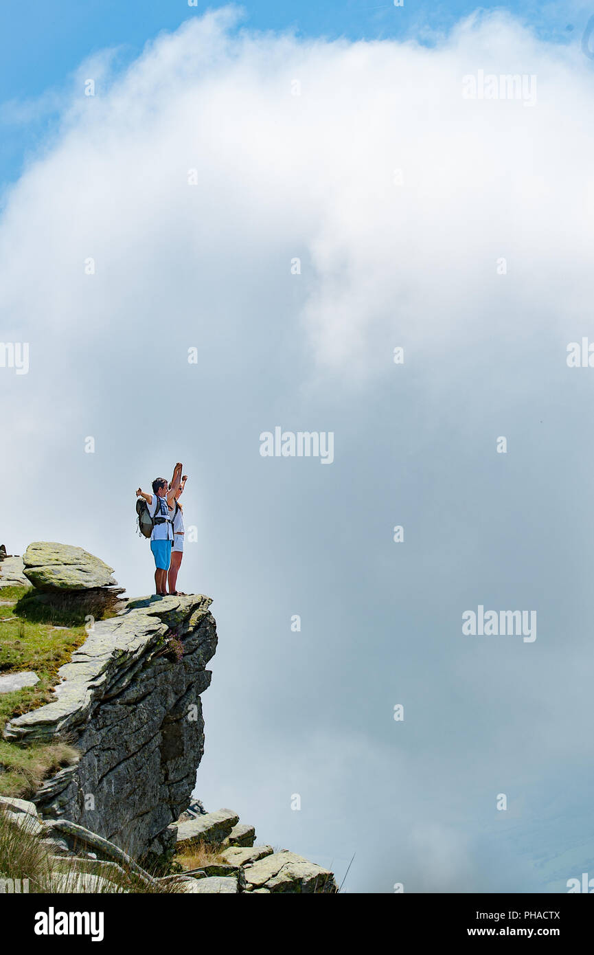 Travel Concept: junge Touristen Paar mit Rucksäcke stehen auf der Spitze einer Klippe mit zunehmender geschwollene weiße Wolke. Kopieren Sie Platz. Stockfoto