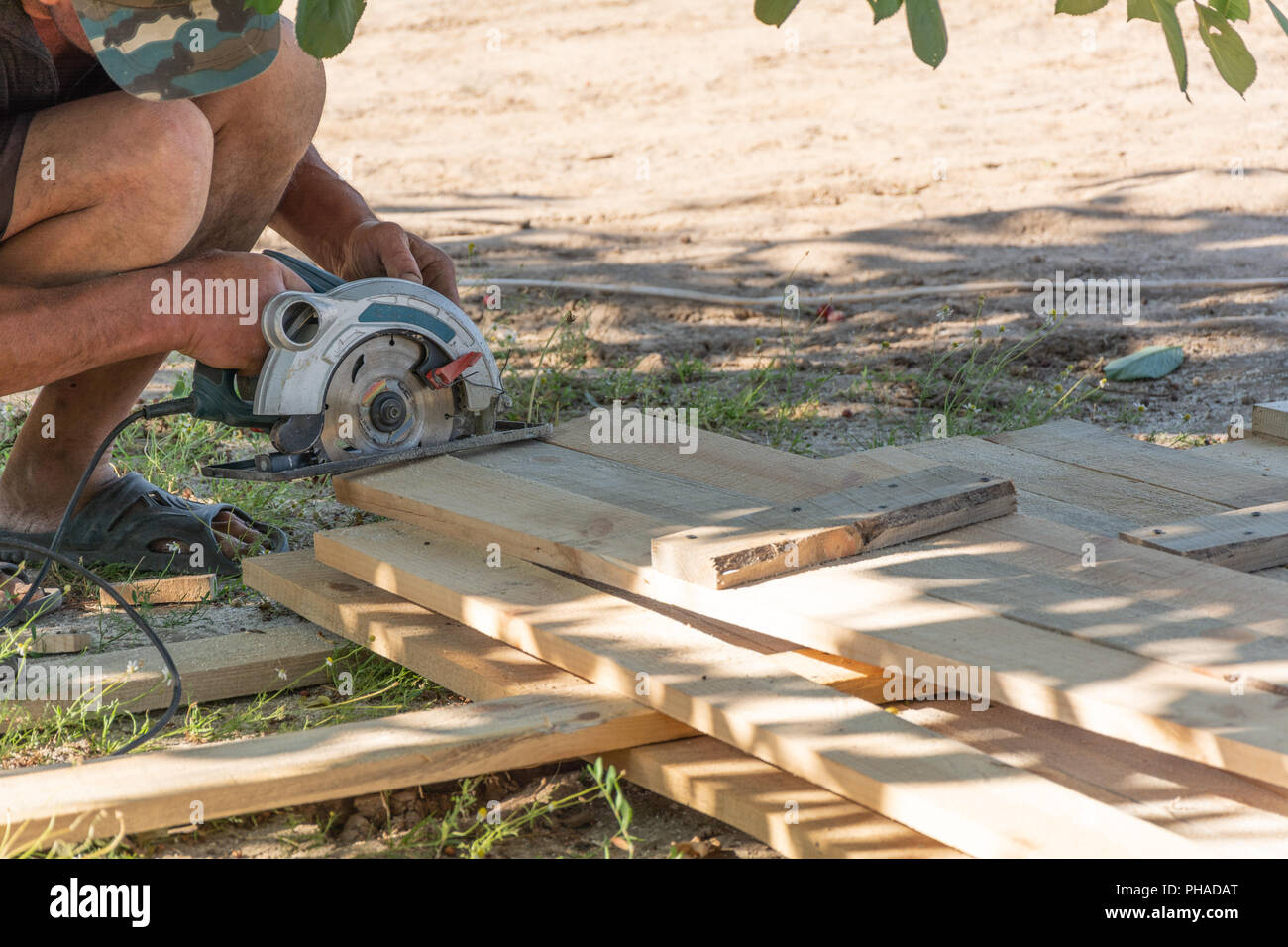 Aufbau einer Schalung für den Zaun. Tischler mit einer Kreissäge ein Holzbrett zu schneiden. Stockfoto