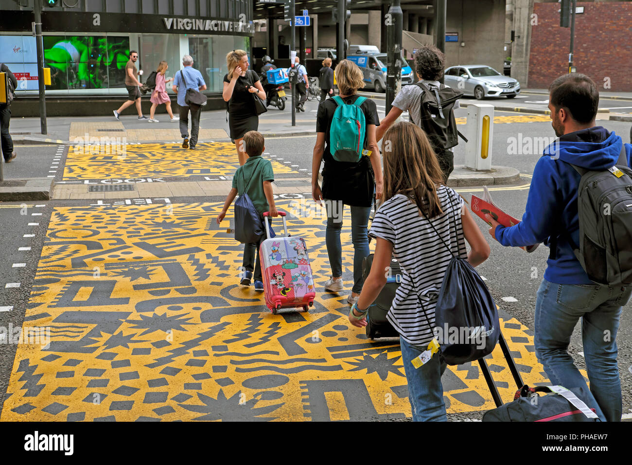 Familie mit Gepäck auf Eley Kishimoto Kunst' farbenfrohe Kreuzungen" Buche Street Tunnel & Barbican Station, Kulturmeile, Stadt London UK KATHY DEWITT Stockfoto