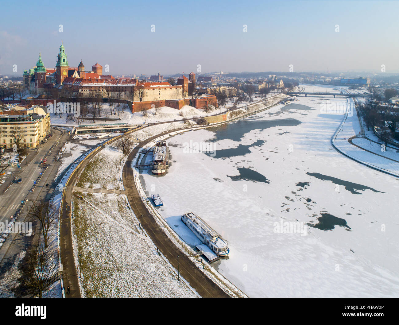 Krakau, Polen, im Winter. Schloss Wawel, der Kathedrale und teilweise gefrorene Weichsel mit Hafen, Schiffe und Grunwaldzki Brücke. Luftaufnahme. Stockfoto
