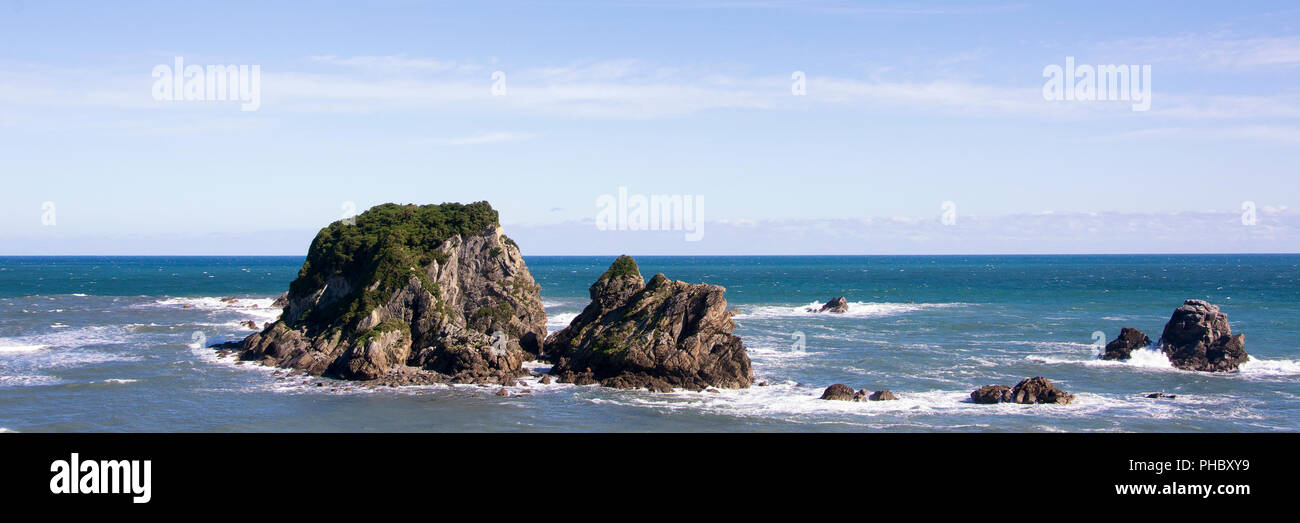 Panoramablick auf die wunderschöne Neuseeland west Küste, mit dem Tasmanischen Meer, Felsen, blaues Wasser und einen klaren Himmel. Raue, ungezähmte Bereich Stockfoto