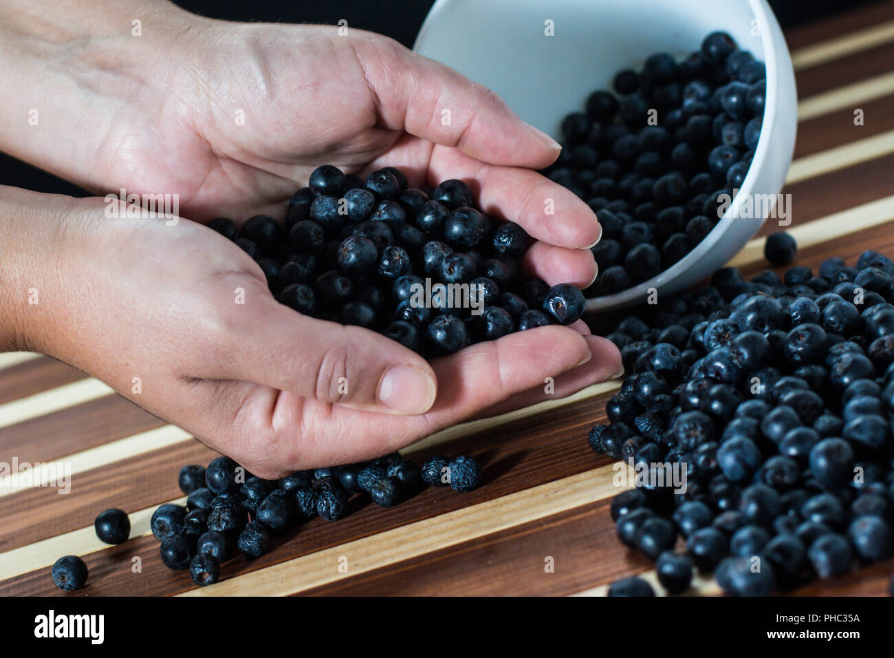 Weibliche Hände mit aronia auf dem Tisch Stockfoto