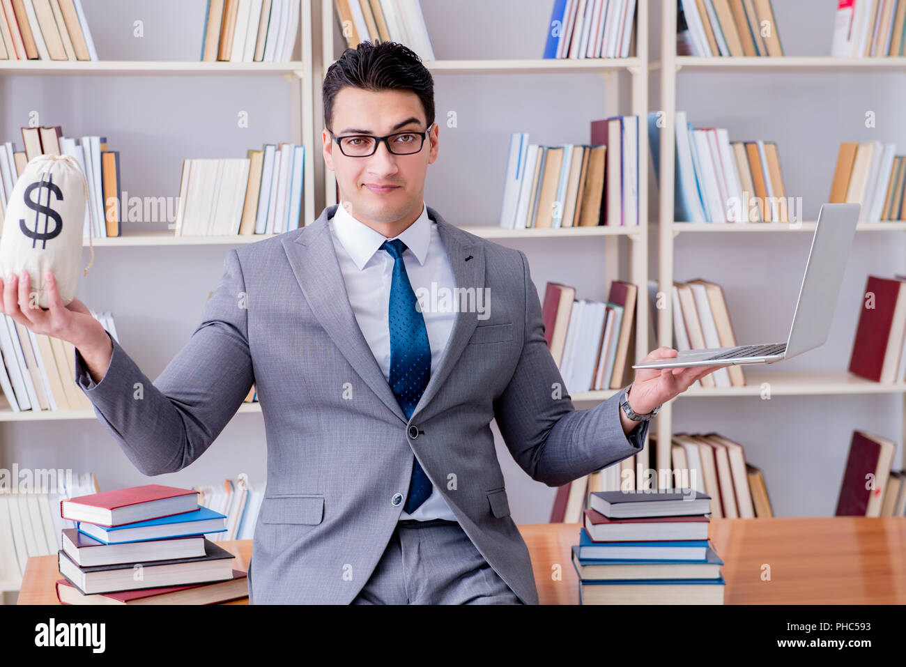 Geschäftsmann in Bibliothek mit meschotschek Geld und laptop Stockfoto