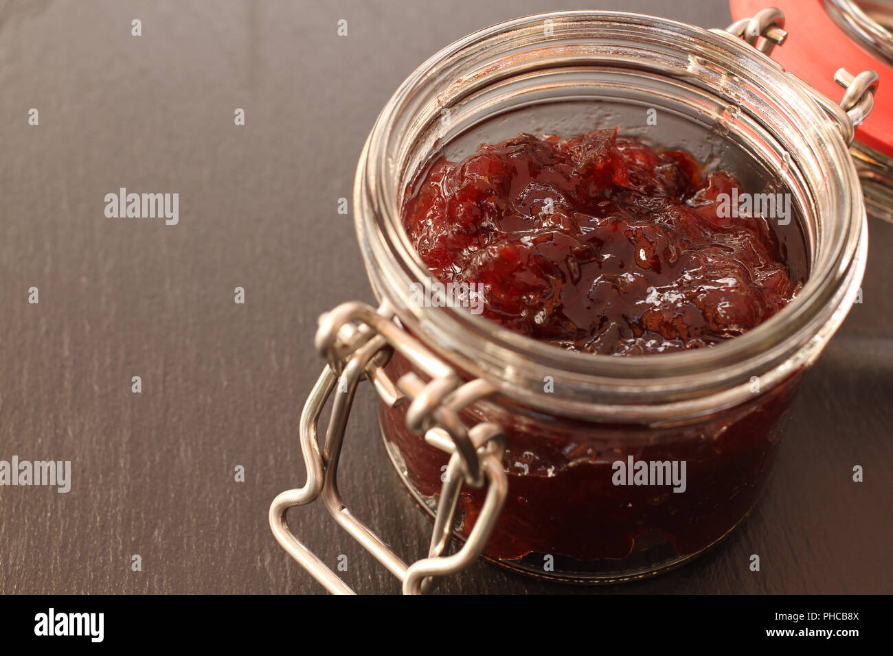 Marmelade im Glas Glas auf schwarzem Hintergrund Stockfoto