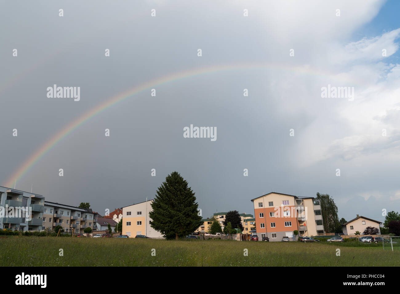 Helle Regenbogen in teilweise bewölktem Himmel im Land Stockfoto