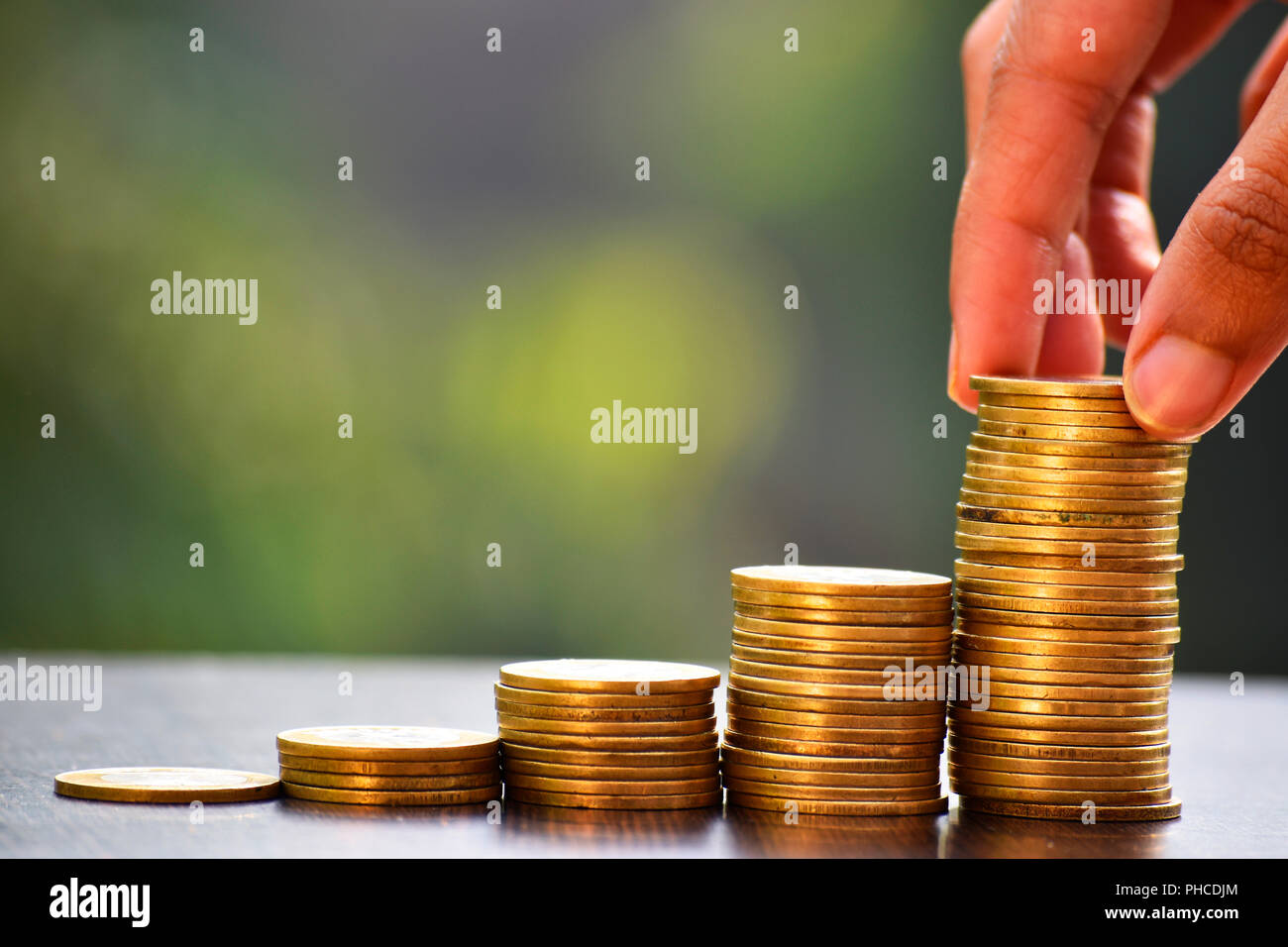 Hand Münzen setzen gegen grünen Hintergrund, Investment, Geld, Umsatz, Chancen, Management, Reichtum, Banking, Konzepte. Stockfoto