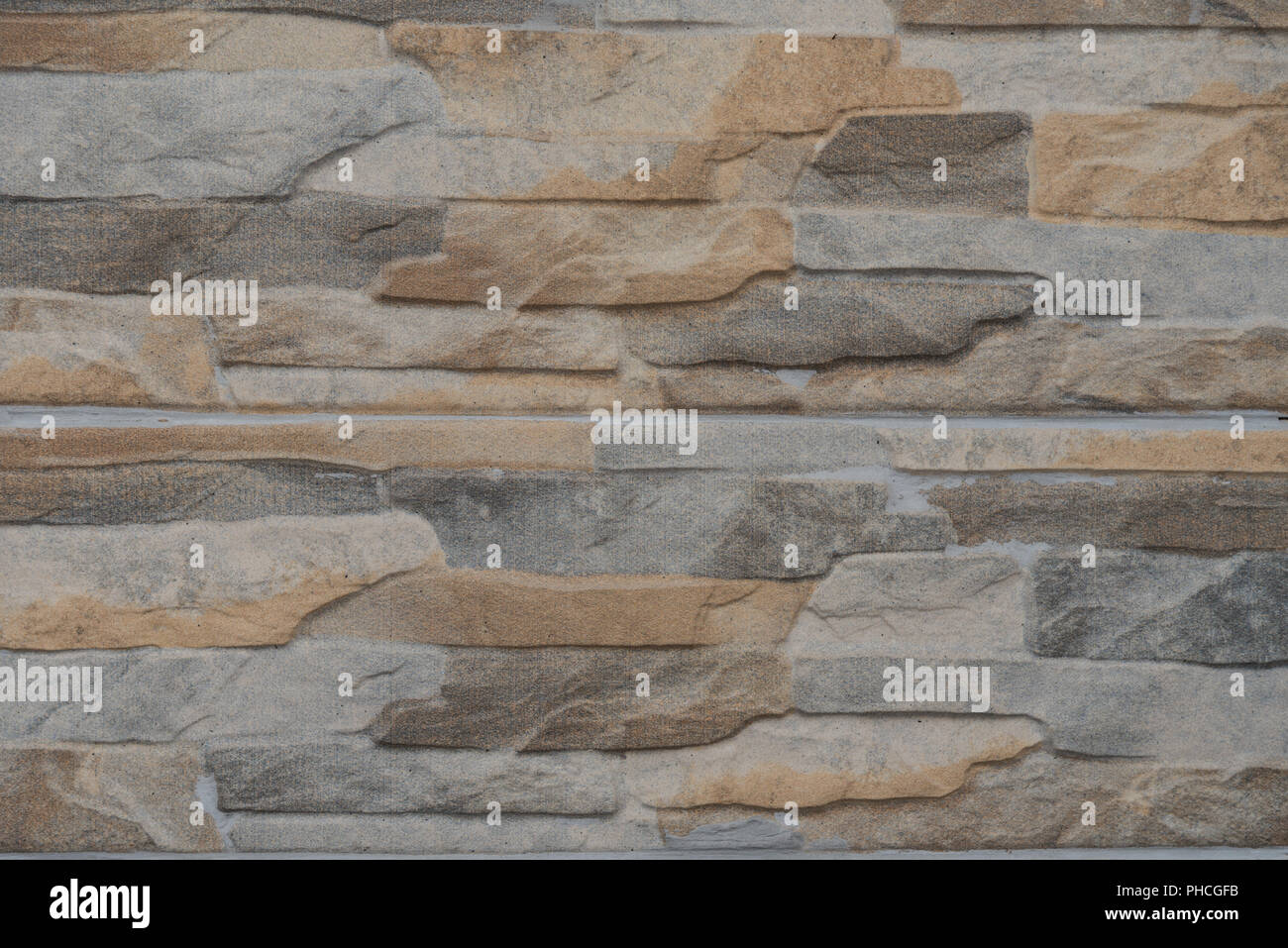 Steinmauer mit relativ glatte Oberfläche und bunte Steine Stockfoto