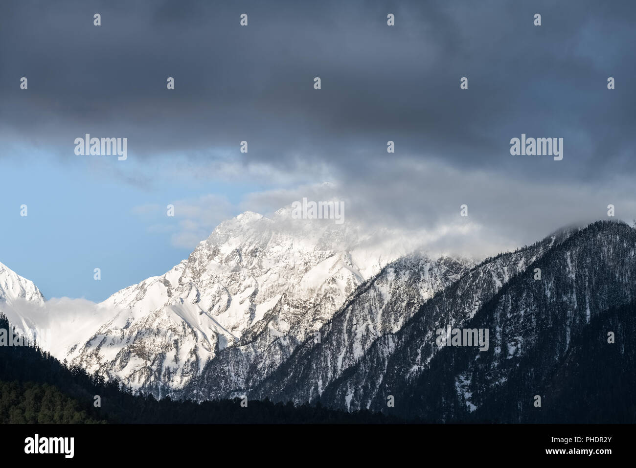 Die schneebedeckten Berge und misty Wolken Stockfoto