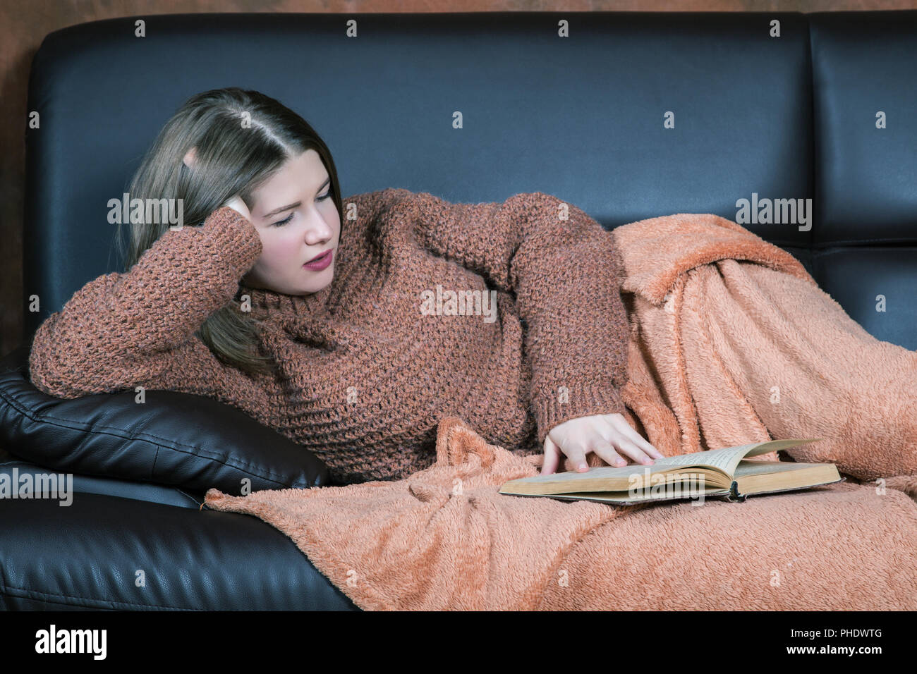 Mädchen mit einem Buch sitzen auf der Couch im Zimmer Stockfoto