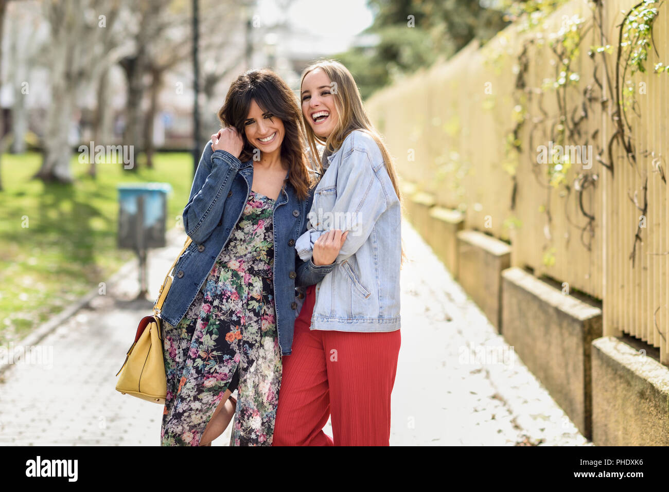 Zwei glückliche junge Frauen Freunde umarmen in der Straße. Blonde und brünette Mädchen legere Kleidung im Freien. Stockfoto
