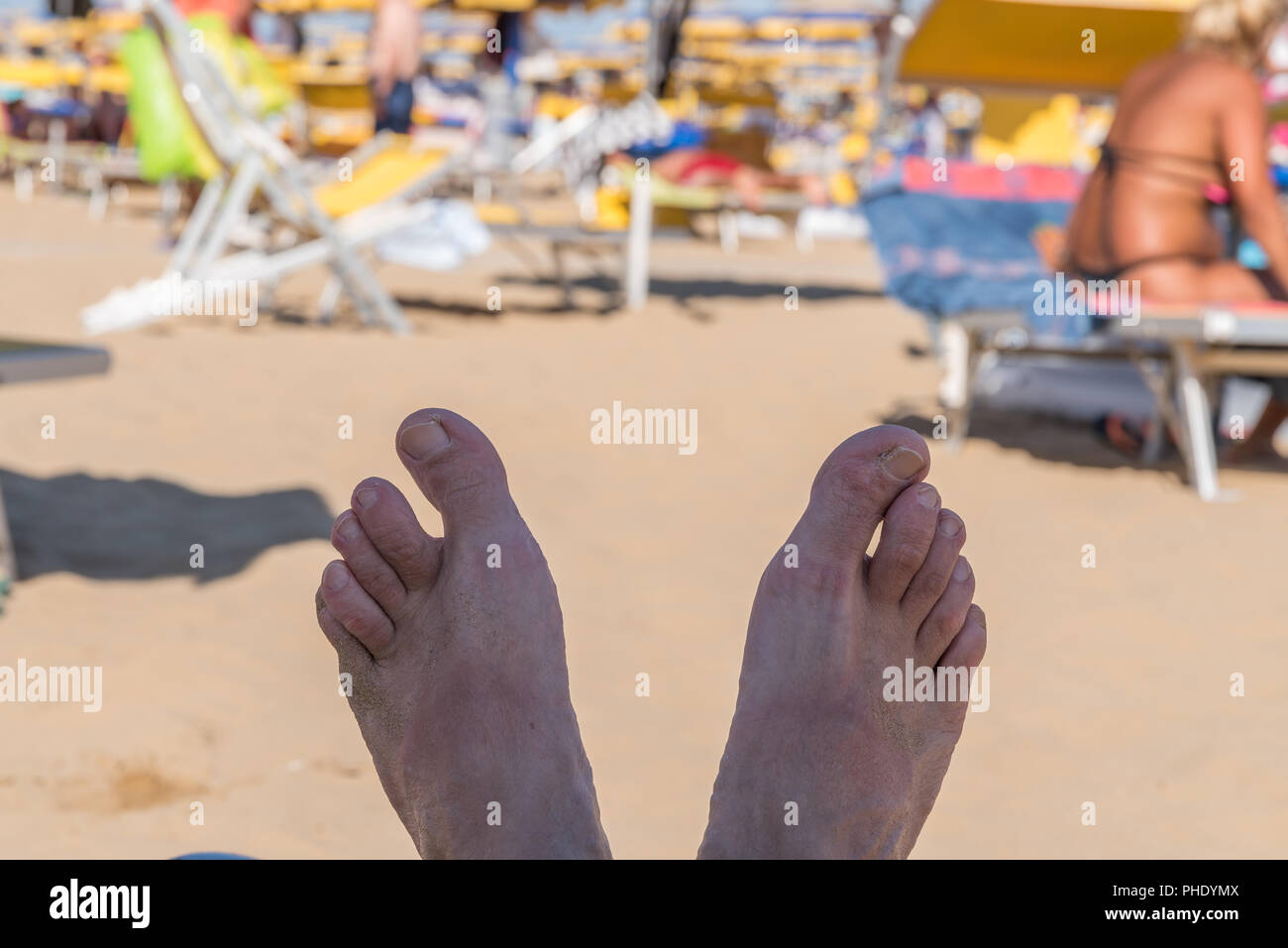 Füße auf eine Sonnenliege am Strand Stockfoto