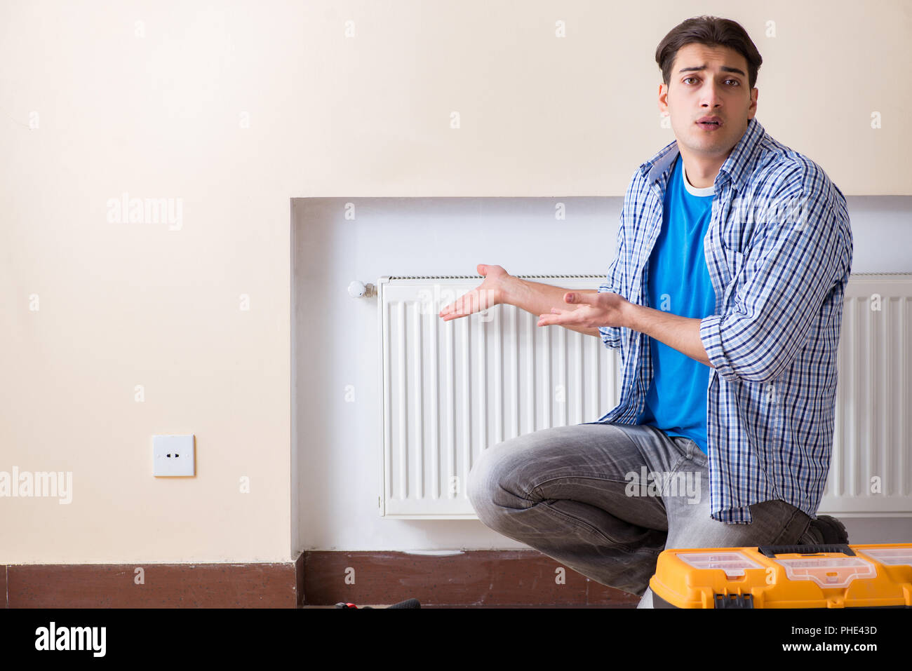 Junge Handwerker Auftragnehmer Reparatur Heizung Panel Stockfoto