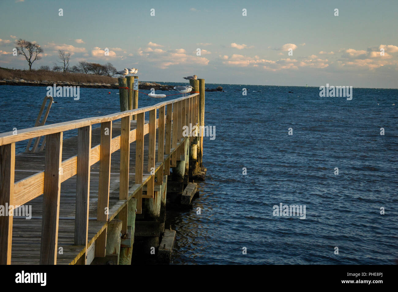 Dock zum Ozean, beleuchtet von der Seite bei Sonnenuntergang Stockfoto