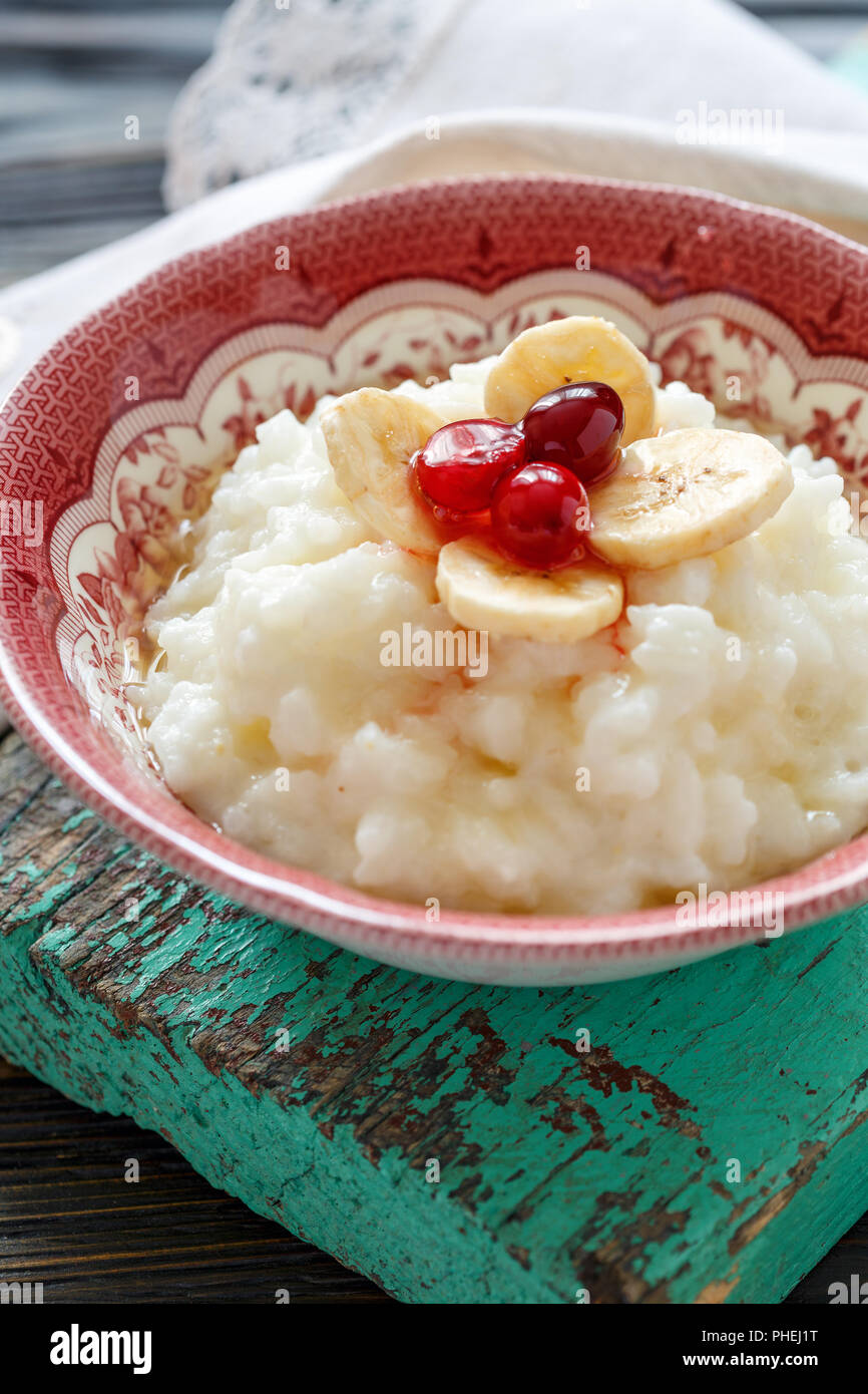 Milch Reisbrei mit Bananen, Beeren und Honig. Stockfoto