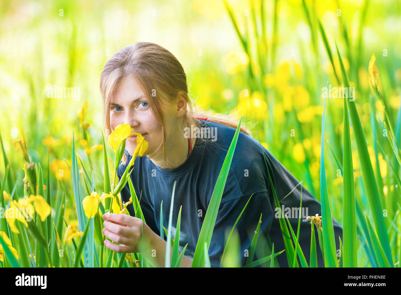 Hübsche blonde Frau riecht gelbe Blüten Stockfoto
