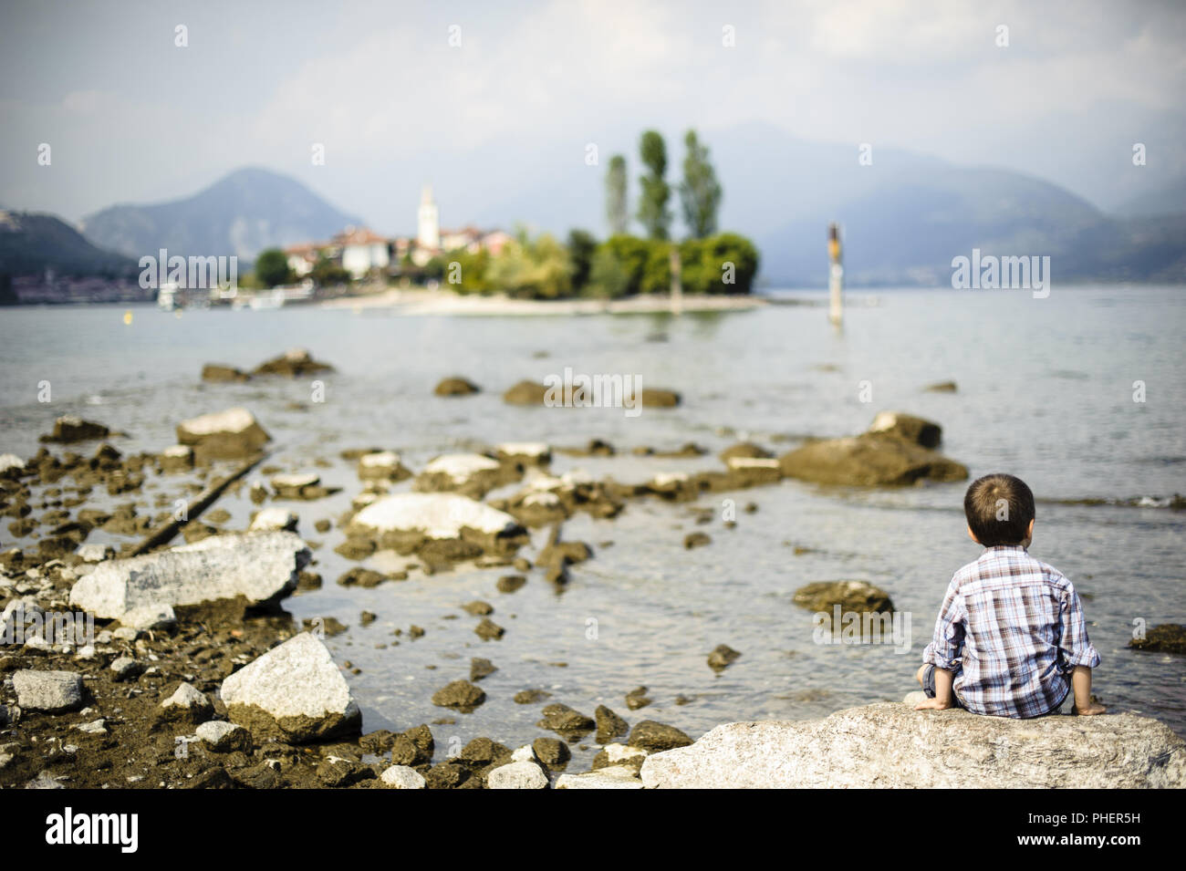 Kind sitzen auf einem Felsen mit Blick auf den Lago Maggiore Stockfoto