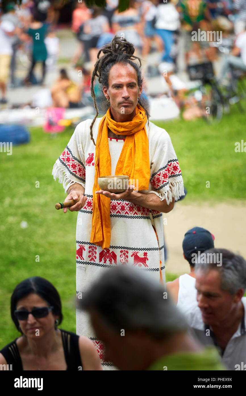 Junge neue alter Hippie Mann von Menschen umgeben hält einen Mörser und Stößel Schleifer in seine Hände in Mount Royal Park, Montreal, Kanada. Stockfoto