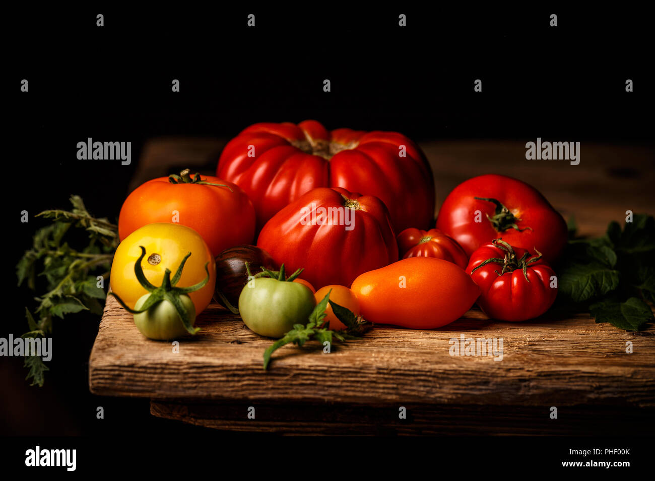 Bunte Tomaten, rot, gelb, orange, grün auf vintage Holztisch Stockfoto